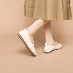 Mocasines retro con detalle de lazo metálico, estilo relajado, en negro, blanco y gris.